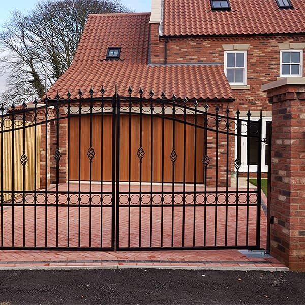 Brick gate pillars with wrought-iron gates on a block-paved driveway