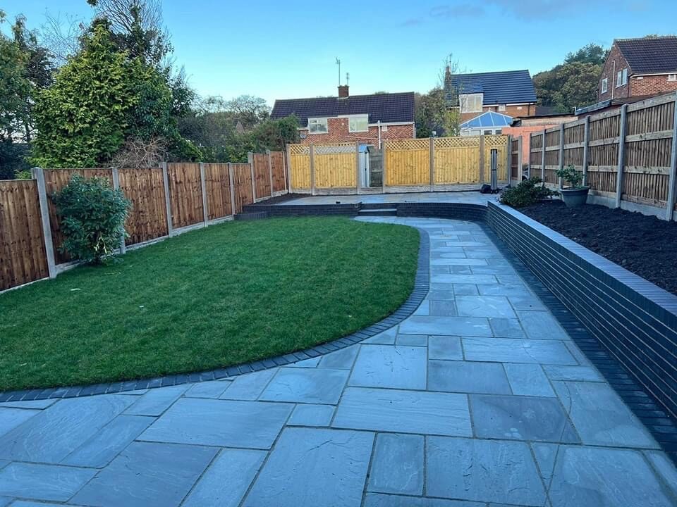 Slate patio with curved lawn edge and low walling, installed in Rochdale